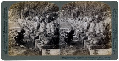 Boer die bidt voor een rij beelden van de God van het Licht, Daiya rivier, Nikko, Japan, 1904 door Underwood and Underwood