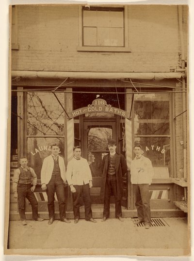 [Vier mannen en een jongen staan voor een openbaar badhuis]. door Unknown artist