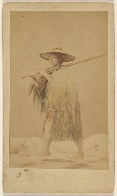 [Japanse man draagt strooien regencape en hoed, en draagt een lange stok]. door Unknown artist