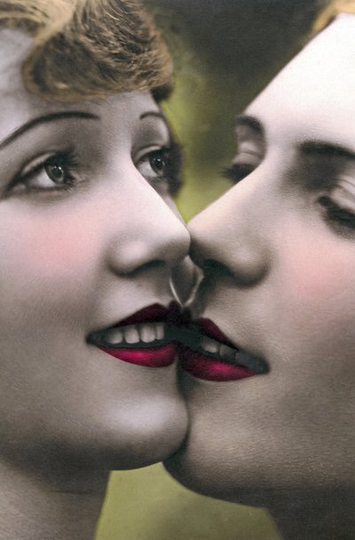 Close-up van gezichten van vrouwen die elkaar een kus op de lippen geven door Unknown photographer