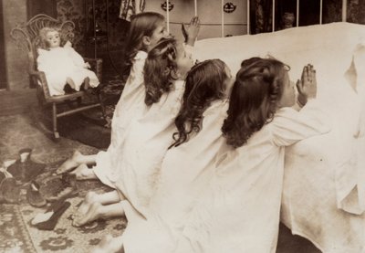 Vier kleine meisjes knielen aan de zijkant van een bed terwijl ze hun avondgebed zeggen door Unknown photographer
