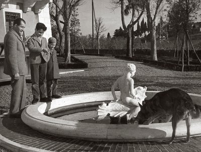 Gino Bartali met twee kinderen en een hond bij een fontein door Unknown photographer