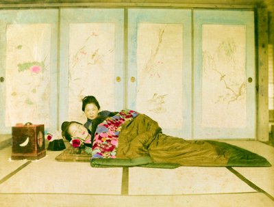 Liggend op een futon. Twee Japanse vrouwen liggen op een traditionele futon op de vloer. Japan, circa 1910. door Unknown photographer