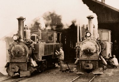 Twee stoomlocomotieven worden onderhouden door twee arbeiders door Unknown photographer
