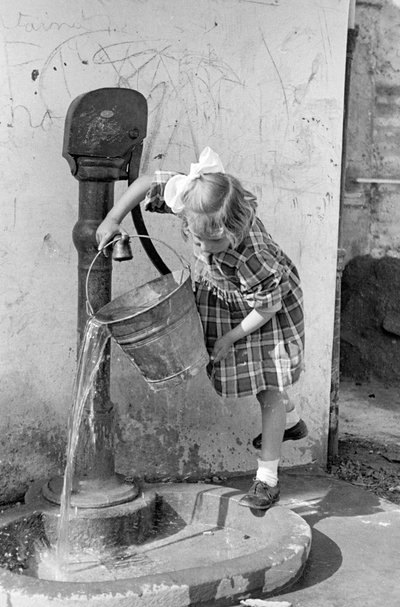 Klein meisje leegt een emmer water in een pompfontein, 9 mei 1939 (z/w foto) door Vincenzo Balocchi