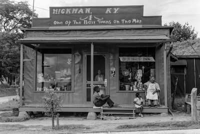 Afrikaans-Amerikaanse mannen en kind ontspannen op de veranda van een kleine algemene winkel aan de rand door Volkmar Wentzel