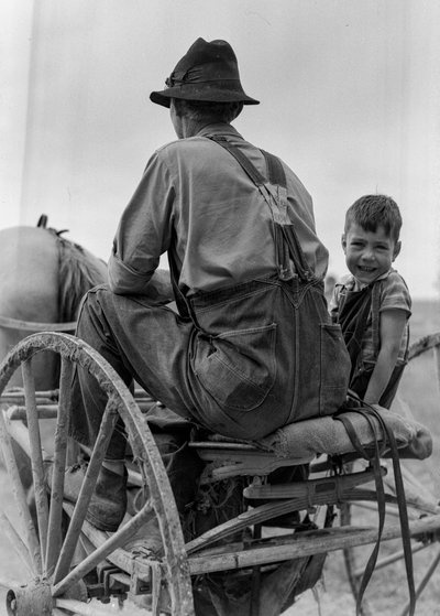 Boer en lachende jongen rijden op de stoel van een paard-en-wagen in West Virginia door Volkmar Wentzel