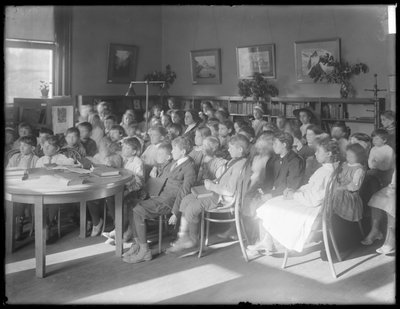 Kinderen zittend, luisterend in de leeszaal van een onbekende vestiging van de Queens Borough Public Library door William Davis Hassler