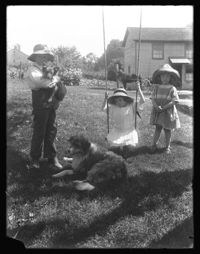 Kinderen met een hond en puppy verzameld rond een touwschommel op de McCready-boerderij, Pennsylvania, c.1913 door William Davis Hassler