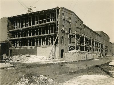Bouwplaats, twee mannen staan in de open zijde van een magazijngebouw; Robbins und Ripley Engineers and Contractors, 23 maart 1916 door William Davis Hassler