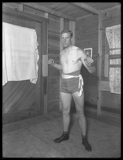 Engelse bokser William Thomas Wells (Bombardier Billy Wells), poserend in trainingskleding met gewichten, ca. 1911 door William Davis Hassler