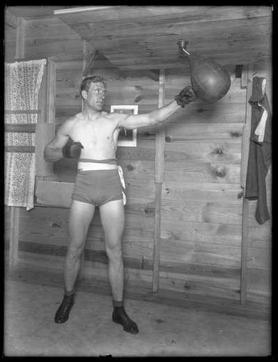 Engelse bokser William Thomas Wells (Bombardier Billy Wells), poserend in trainingskleding met een snelheidszak, ca. 1911 door William Davis Hassler