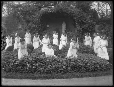 Afstudeerklas van meisjes van het Rooms-Katholieke Weeshuis in de bloementuin, voor de grot van de Maagd Maria, 1912 door William Davis Hassler