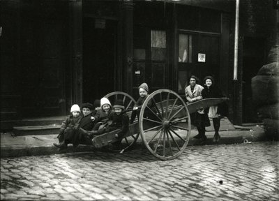 Groep kinderen in kar, met meisje en vrouw staand erachter, ca. 1910-21 door William Davis Hassler