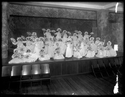 Groep kleine meisjes geposeerd op een klein podium met waaiers, waarschijnlijk het Rooms-Katholieke Weeshuis, Kingsbridge, Bronx, ca. 1911 door William Davis Hassler
