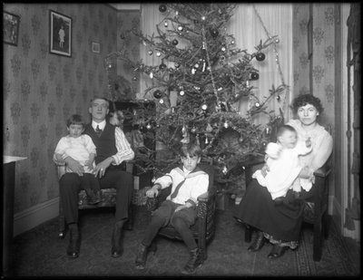 Informele groepsportret van een onbekende familie in hun appartement voor een kerstboom, New York City, ca. 1915-16 door William Davis Hassler