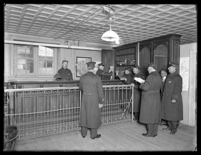 Interieur van een niet-geïdentificeerd politiebureau, met agenten en balie, ca. 1913-14 door William Davis Hassler