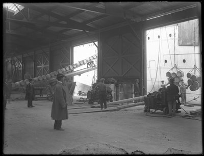 Interieur magazijn aan de kade, draagbare elektrische lieren worden gebruikt om schip te lossen, 31st Street, Brooklyn, 1912 door William Davis Hassler