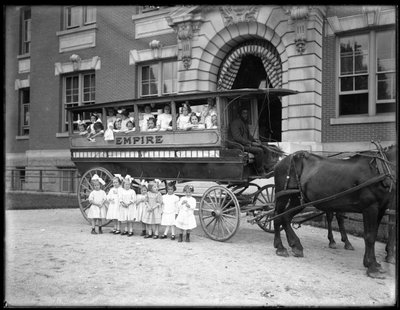 Kleine meisjes poseren in en voor een door paarden getrokken wagen, voor een onbekend gebouw, waarschijnlijk het Rooms-Katholieke Weeshuis, Kingsbridge, Bronx, c.1910 door William Davis Hassler