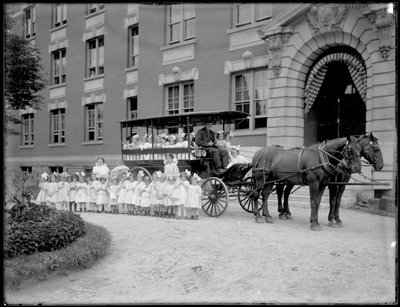 Kleine meisjes poseren in en voor een door paarden getrokken wagen, voor een onbekend gebouw, waarschijnlijk het Rooms-Katholieke Weeshuis, Kingsbridge, Bronx, c.1910 door William Davis Hassler