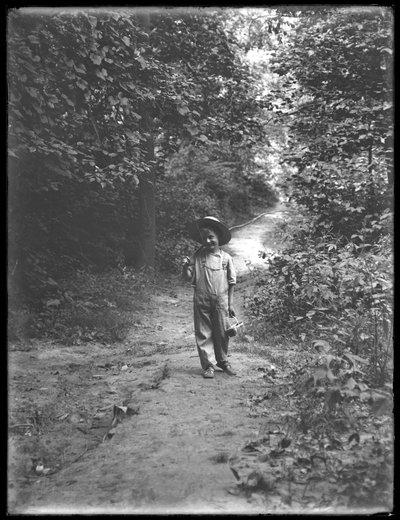 William Gray Hassler met Strohoed en Overall, met Hengel en Mand, wandelend op een Pad in het Bos door William Davis Hassler