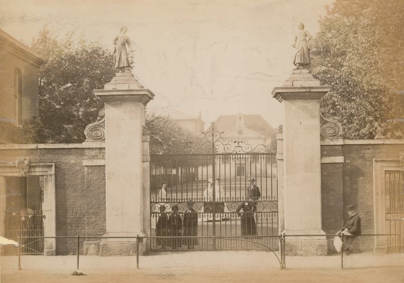 Kinderen staan te kijken door het schoolhek door English Photographer
