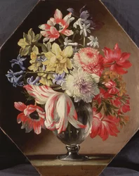 Een glazen vaas met bloemen op een stenen richel met tulpen, chrysanten, rozen en blauwe klokjes