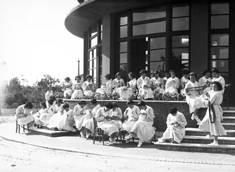 Villa Rosa Maltoni Mussolini: vrouwelijke studenten tijdens een naailes, buiten (zw/w foto)