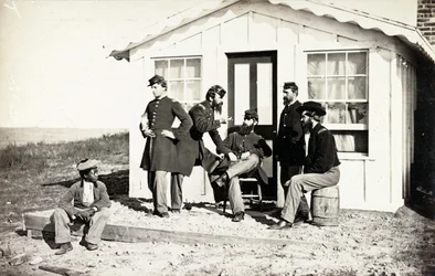 Vijf soldaten uit de Burgeroorlog verzameld op een veranda, Afro-Amerikaanse jongen zit bij hen, 1861-65