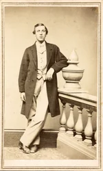 Onbekende man in overjas leunend tegen een pilaar, ca. 1860-75