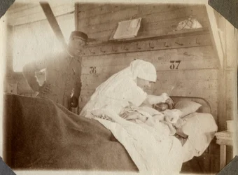 Eerste Wereldoorlog 1914-1918: verpleegster in een blouse scheert een soldaat (Franse oorlogswonden liggen in een bed), in Couville, Manche, Basse-Normandie, Frankrijk. Anonieme foto juli 1917. Privécollectie, Stella.
