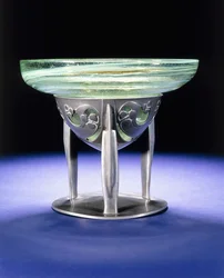 Een Liberty Tudric tinnen schaal met James Couper & Sons Clutha glazen voering, ca. 1902-05