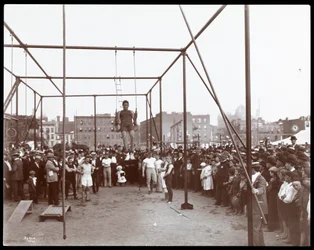 Menigte kijkt naar een gymnast in de Hudson Bank Gymnasium en Speelplaats, 53rd Street en 11th Avenue, New York, 1898