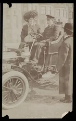Hattie Williams zittend met chauffeur in een van de eerste auto