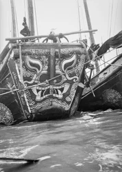 De sterk decoratieve boeg van een handelsjonk van het type Hangchow Bay, afgemeerd met andere jonken in Shanghai