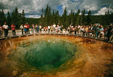 Parkbezoekers verzamelen zich rond een blauwgroene, bloemvormige warmwaterbron. Yellowstone National Park