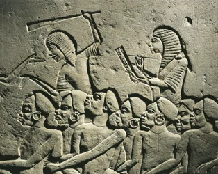 Een groep zwarte gevangenen omringd door met knuppels bewapende wachters, terwijl een schrijver een verslag opstelt. Reliëf uit het graf van Horemheb in Saqqara, detail