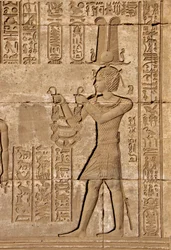 Egyptische oudheid: Romeinse mammisi ter herdenking van de geboorte van Ihy, zoon van Isis - Detail van reliëfs en hiërogliefen: Keizer Trajanus die offers brengt aan de godin Hathor - Tempel van Hathor, Denderah, Egypte