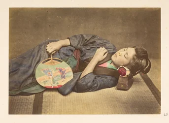 Japanse vrouw slapend, Driekwart lengte studiportret van een jonge Japanse vrouw slapend, met een waaier in haar rechterhand en haar hoofd rustend op een houten kussen, Fotograaf: Onbekend Lucas Collectie: Fotografisch verslag van de wereldreis van Charles