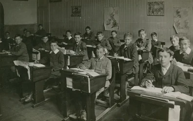 Mannelijke leerlingen zitten achter hun bureaus tijdens een les op school