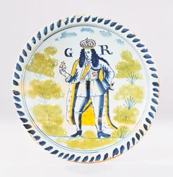 Een Bristol Delft polychroom koninklijk portret bord beschilderd met een volledige lengte portret van George I in formele gewaden, ca. 1720