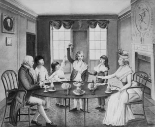 Een interieur met een dame en heer zittend aan een tafel met hun vier kinderen staand erachter, ca. 1780