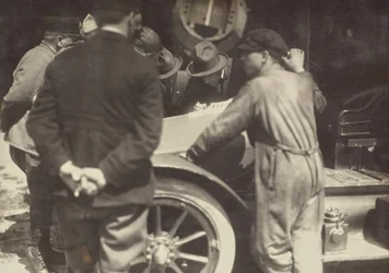 [Mannen gegroepeerd rond de motorkap van een auto].