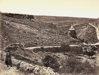 Panoramisch uitzicht op de Vallei van Cedron of Josafat, met het graf van Absalom, aan de rand van Jeruzalem. Een man kijkt naar het uitzicht vanaf de straat