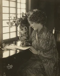 Mary Pickford, gekleed in een kimono, schrijvend aan een bureau, ca. 1918