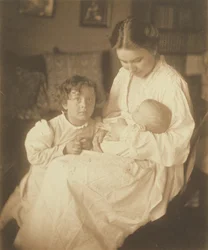 [Moeder in kamerjas, zittend, met baby en zoontje].