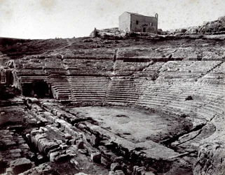 De overblijfselen van het Griekse Theater in Siracusa in het Monumentale Park van de Neàpoll. Op de voorgrond de halfronde orkestbak en de cavea