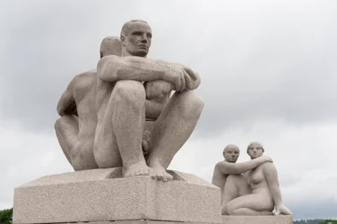 Granieten sculpturen van twee naakte mannen die rug aan rug zitten; sculptuur van twee vrouwen aan de achterzijde van een sculptuur in het Frognerpark, Oslo, Noorwegen