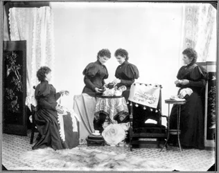 Meervoudige belichting van Hannah Maynard - twee drinken thee, een houdt een streng katoen vast, een windt die tot een bol, ca. 1895