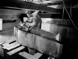 Ontdekking van het graf van farao Toetanchamon in de Vallei der Koningen (Egypte): in de grafkamer werkt Howard Carter aan het deksel van de tweede kist, oktober 1925, foto van Harry Burton (p1568)